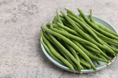 Fresh green bean pods on grey textured table, closeup. Space for text