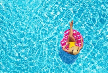 Yüzme havuzunda şişirilebilir yüzüklü genç bir kadın.