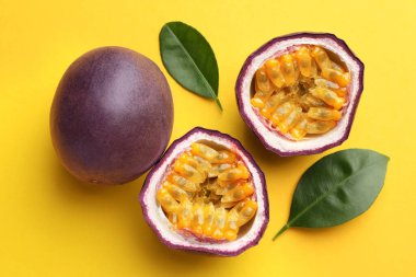 Fresh passion fruits with green leaves on yellow background, above view