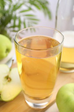 Bardakta taze elma şarabı, masada şişe ve elma, yakın plan.