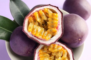 Mor arka planda yeşil yapraklı taze tutku meyveleri, yakın plan.