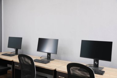 Ofisin içini aç. Açık gri duvarın yanında bilgisayarları olan modern işyerleri