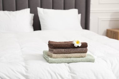 İçerideki yatağın üzerinde havlu ve tesisat çiçeği yığını.