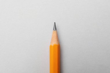 Gri arkaplanda keskin bir grafit kalem, üst görünümde.