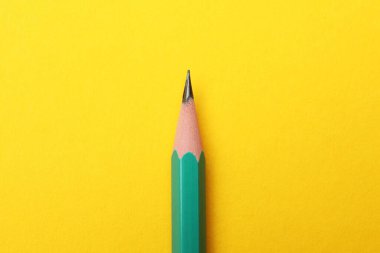 Sarı arkaplanda keskin bir grafit kalem, üst görünümde.
