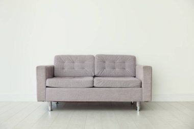 Beyaz duvarın yanındaki rahat gri kanepe.