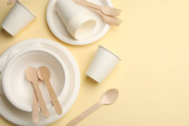 Bej arka planda tek kullanımlık sofra takımı, düz konum. Metin için boşluk