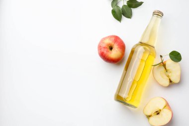 Cam şişede nefis elma şarabı, beyaz arka planda elmalar ve yeşil yapraklar, düz yatak. Metin için boşluk