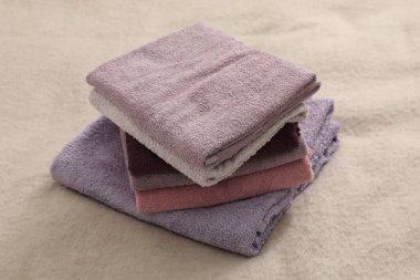 Stack of terry towels on beige blanket, closeup
