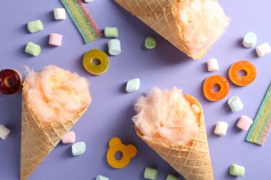 Waffle külahında pamuk şeker ve menekşe arka planda farklı tatlılar, düz uzanma