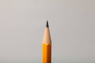 Gri arkaplanda keskin bir grafit kalem, yakın plan.