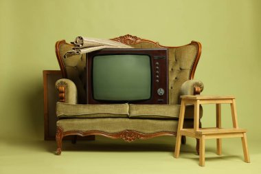 Retro TV seti, kanepe, zeytin arka planda iskemle ve halı. Kullanılmış eşyalar
