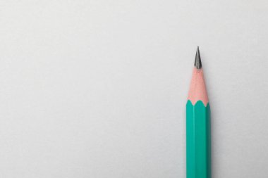 Gri arka planda keskin bir grafit kalem, üst manzara. Metin için boşluk