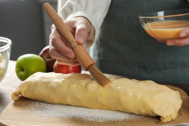 Mutfaktaki çiğ elmalı turtaya yumurta sarısı döken kadın, yakın plan.