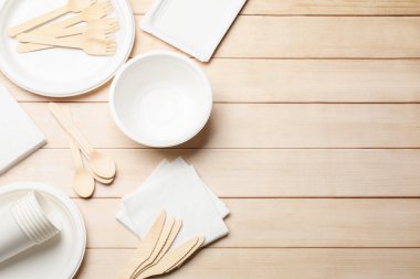 Tek kullanımlık sofra takımı ve peçeteler ahşap masada, düz yerde. Metin için boşluk
