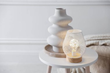 Stylish lamp and vase on white table indoors, space for text
