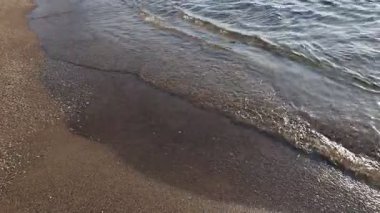 Güneşli bir günde güzel dalgalı deniz ve kumlu sahil, kamera sağa hareket ediyor.