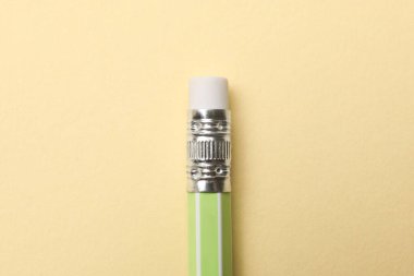 One graphite pencil on beige background, above view