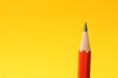Sarı arka planda keskin bir grafit kalem, yakın plan. Metin için boşluk