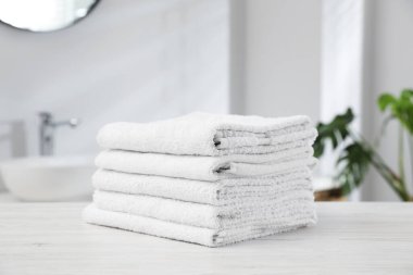 Katlanmış havlular banyodaki açık ahşap masada, yakın plan.