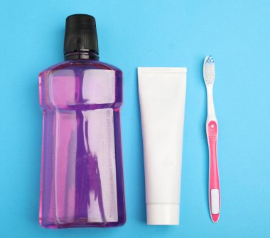 Açık mavi zemin üzerinde gargara, diş fırçası ve diş macunu.