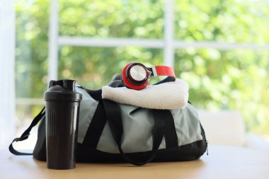 Evdeki ahşap masada spor malzemeleri olan şık bir çanta.