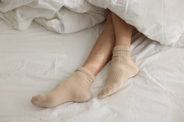 Beyaz çarşaflı, çoraplı bir kadın.
