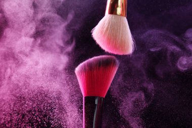 Renkli göz gölgeli makyaj fırçaları siyah arka planda neon ışıkları, yakın plan