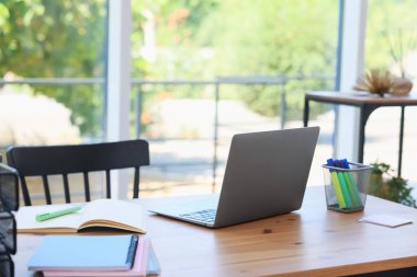 Ev çalışma alanı. Modern laptop ve kırtasiye malzemeleri ahşap masa içinde.