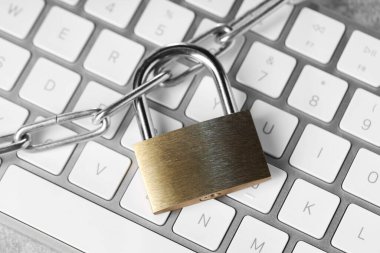 Cyber safety. Metal padlock, chain and computer keyboard on grey table, top view