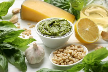 Tabakta taze pesto sosu ve beyaz ahşap masada malzemeler, yakın plan.