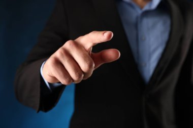 Adam mavi arkaplanda bir şeye dokunuyor, yakın plan.