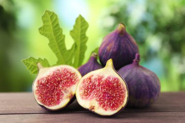 Taze incir ve yeşil yaprak dışarıda, ahşap masada, yakın plan.