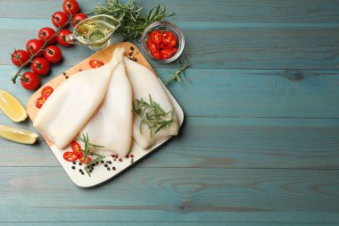 Mavi ahşap masada baharatlı pişmemiş mürekkep balıkları. Metin için boşluk