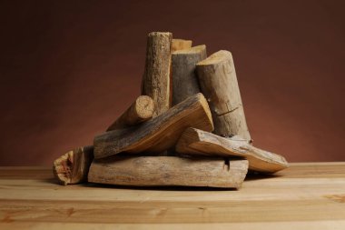 Kahverengi arka planda tahta masa üzerine kesilmiş odun yığını
