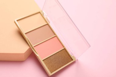 Colorful eyeshadow palette and podium on pink background, closeup. Space for text