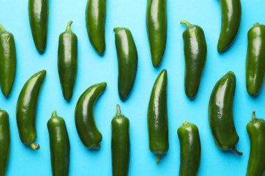 Açık mavi arka planda yeşil biberler, düz uzanmış