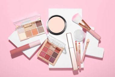 Renkli göz falı paletleri ve pembe arka planda diğer kozmetik ürünleri ile düz kompozisyon yatıyordu