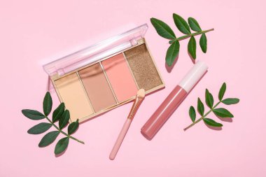 Flat lay composition with colorful eyeshadow palette, and lipstick on pink background