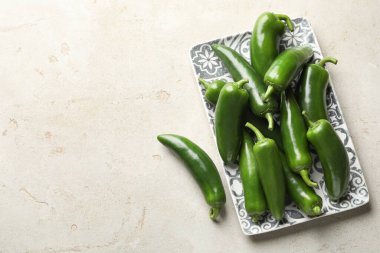 Fresh jalapeno peppers on light textured table, top view. Space for text