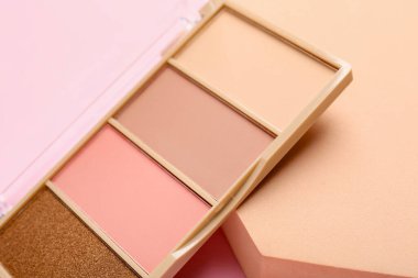 Colorful eyeshadow palette and podium on pink background, closeup