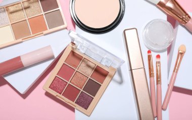 Renkli göz falı paletleri ve pembe arka planda diğer kozmetik ürünleri ile düz kompozisyon yatıyordu