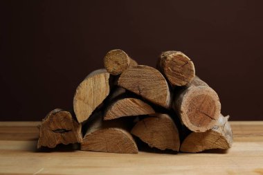 Ahşap masa üzerine kesilmiş odun yığını kahverengi arka plana karşı, yakın plan