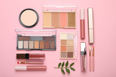 Renkli göz falı paletleri ve pembe arka planda diğer kozmetik ürünleri ile düz kompozisyon yatıyordu