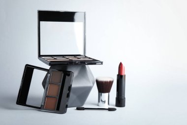 Eyeshadow palettes, lipstick and brushes on white background