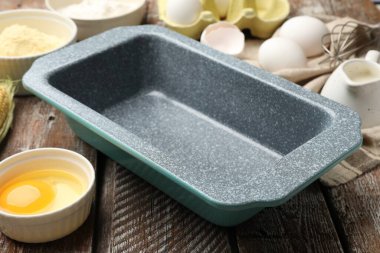 Making cornbread. Baking dish and different ingredients on wooden table, closeup