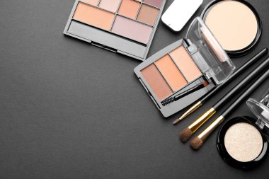 Göz farı paletleri, diğer kozmetik ürünler ve siyah arka planda fırçalar, düz yatış. Metin için boşluk