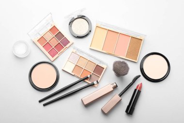Eyeshadow palettes, other cosmetic products and brushes on white background, flat lay