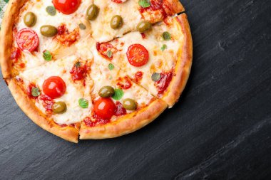 Delicious pizza with cheese, tomatoes and olives on black table, top view. Space for text