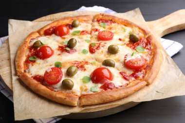 Delicious pizza with cheese, tomatoes and olives on black wooden table, closeup